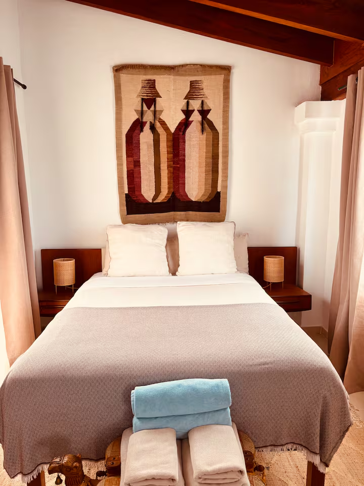 Attic bedroom with woven tapestry above the bed